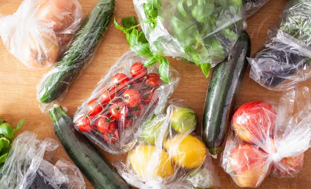 Various fruit and vegetables wrapped in plastic film.