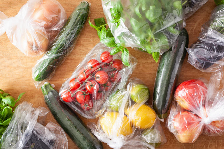 Various fruit and vegetables wrapped in plastic film.