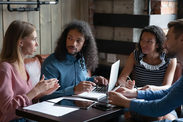 Four students sit discussing at a table.