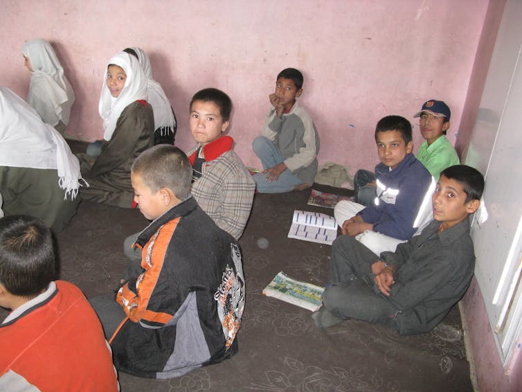 Boys sit on the ground in a school.