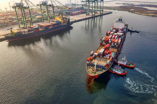 Tug boats push a large cargo ship in port.