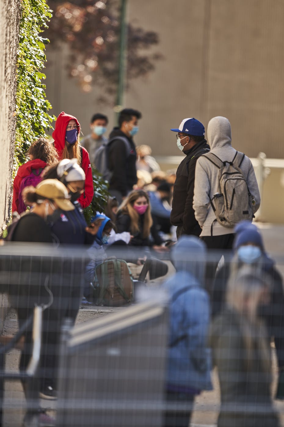 Students stand in a line on campus wearing face masks.