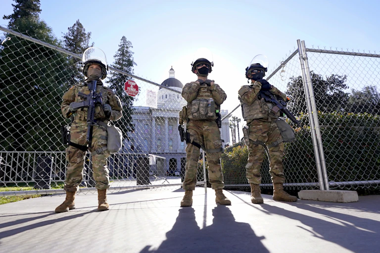 Armed soldiers stand near a fence outside the California Capitol building