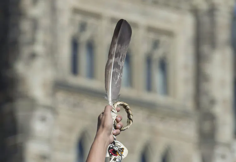 An eagle feather is held up during a rally.