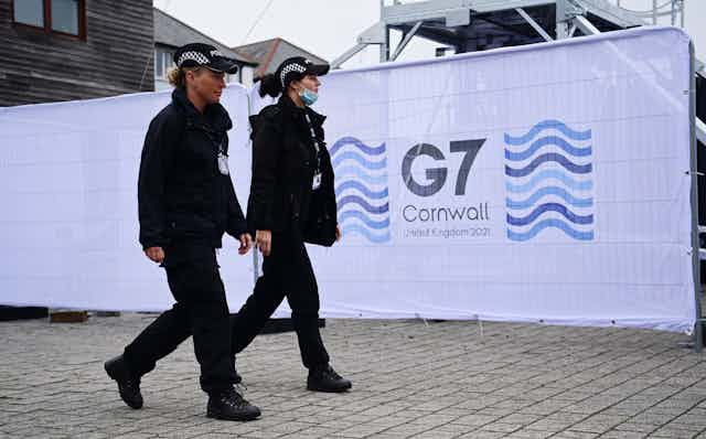 Police officers walking past a G7 Summit sign