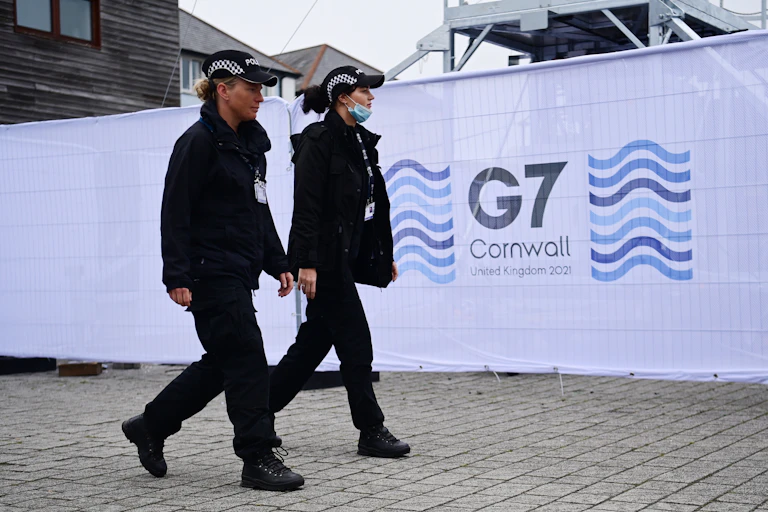 Police officers walking past a G7 Summit sign