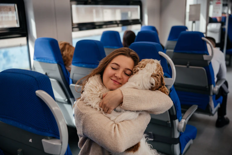 Young woman hugs her dog while travelling on a train