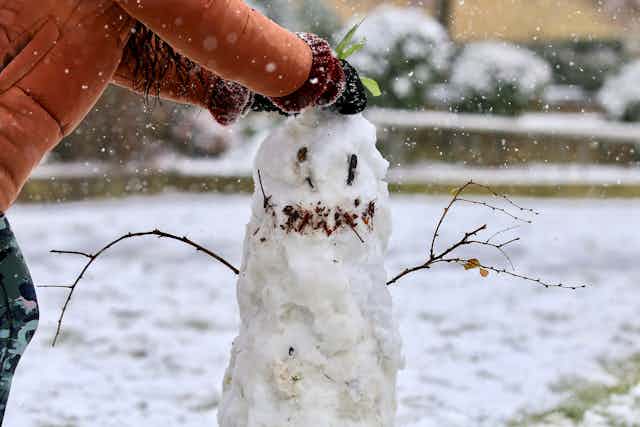 child builds snowman