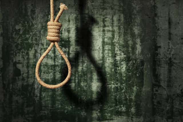A hangman's noose hangs ominously against a dark background.