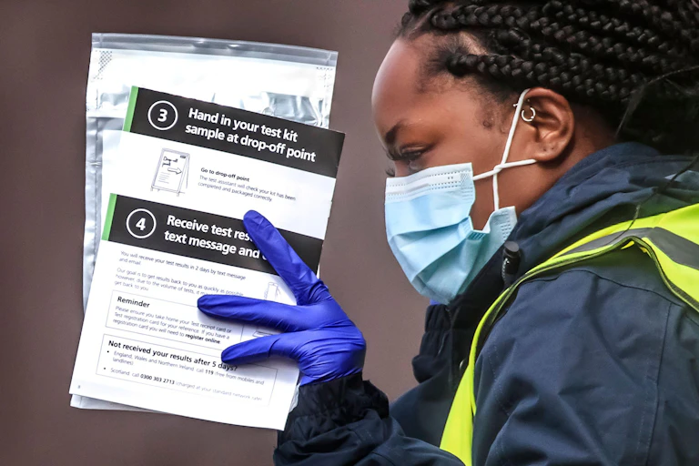 A woman hands out self-test kits at a COVID testing centre in Bolton, England.