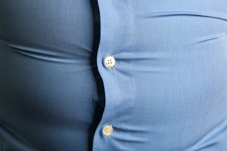 Camisa azul apretada por culpa de la barriga.