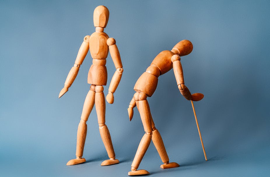 Two wooden artist figures representing a young healthy body and a stooped, ageing one with walking stick.