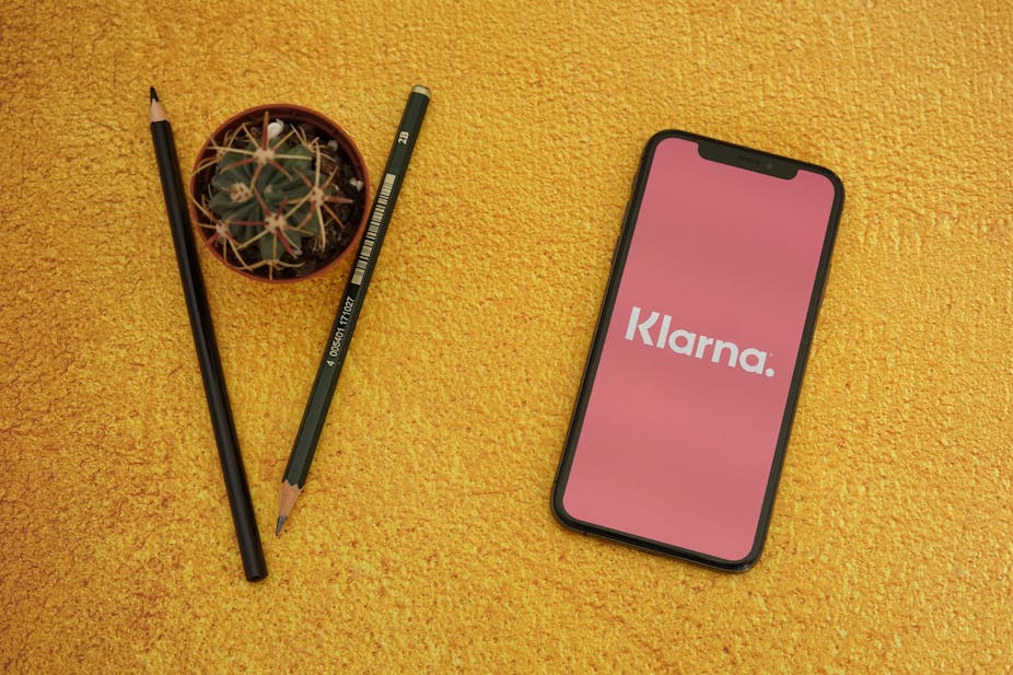 Phone with Klarna app next to a couple of pencils