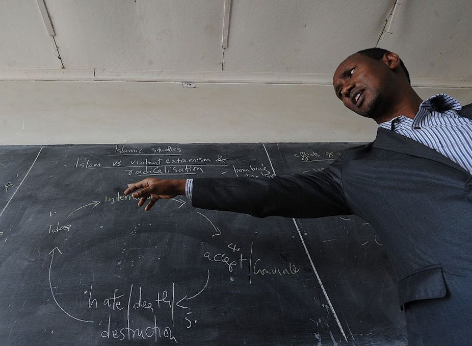 Kenyan teacher giving a lesson in front of a blackboard.