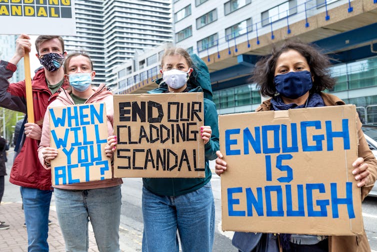 Protestors carry signs saying 'WHEN WILL YOU ACT?' 'END OUR CLADDING SCANDAL', and 'ENOUGH IS ENOUGH'.
