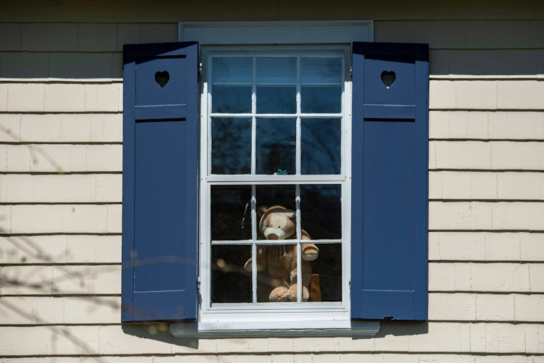 A stuffed bear is visible through a window