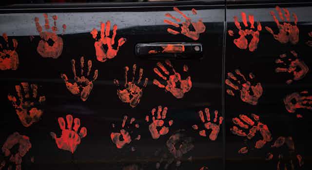 Handprints representing 215 Indigenous childrenare seen on the side of a truck.