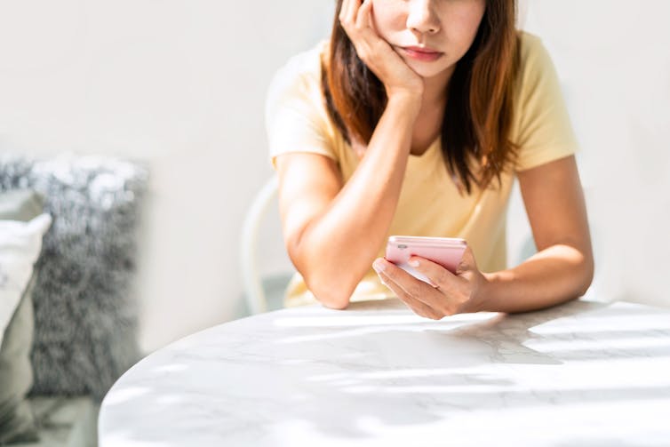 Woman looking bored on her phone.