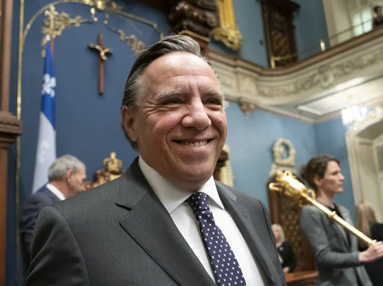 The crucifix hangs on the wall behind François Legault