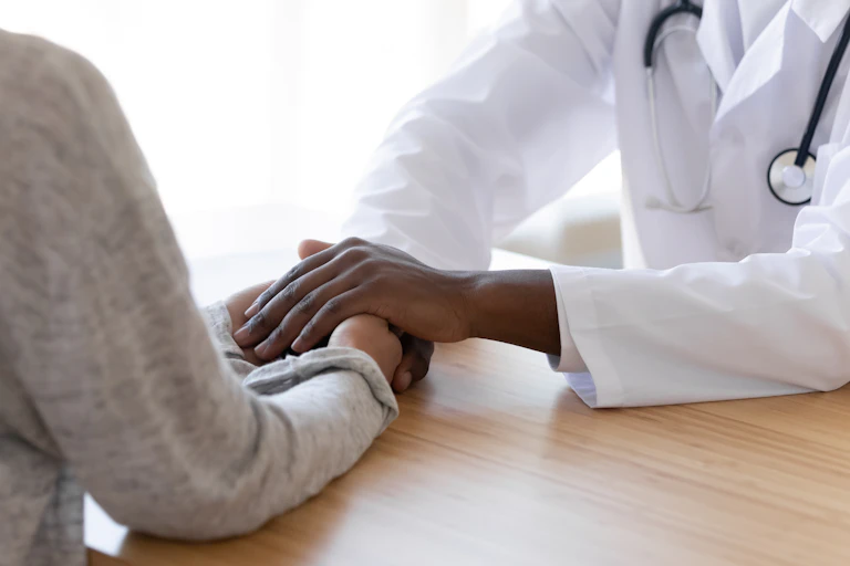A doctor's hands clasping a patient's hands.