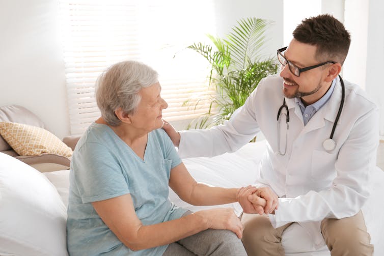 A male doctor consulting with an older female patient