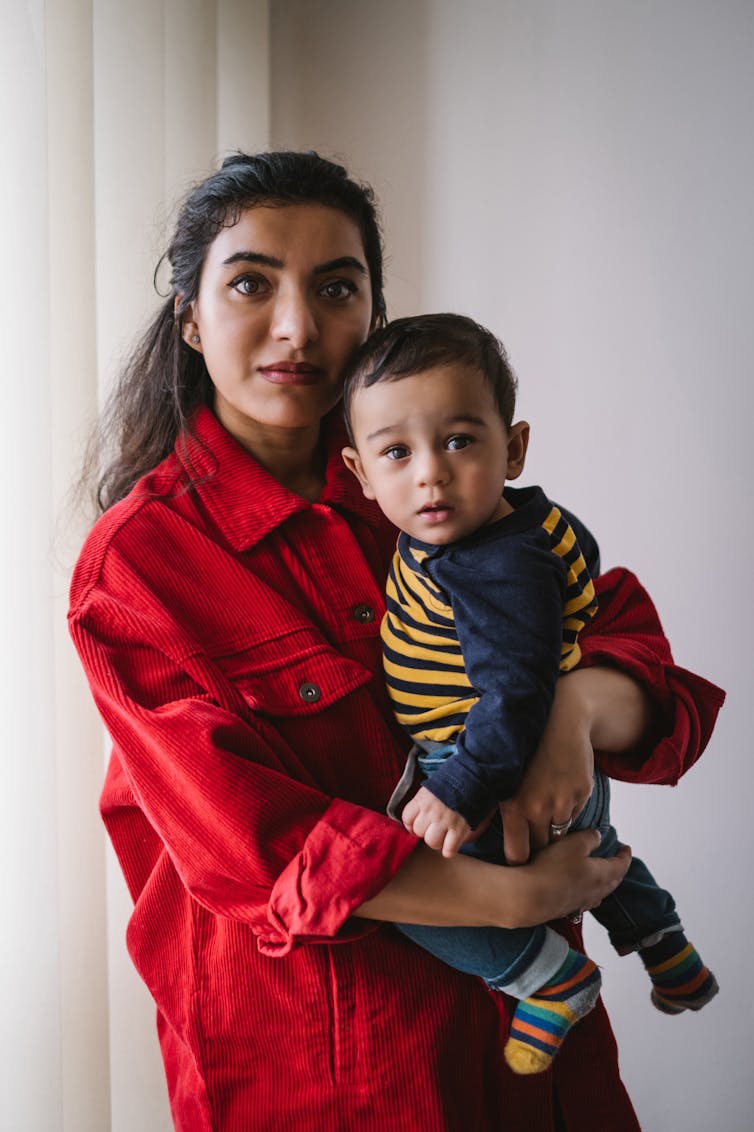 Pakistani woman in red shirt holding her son