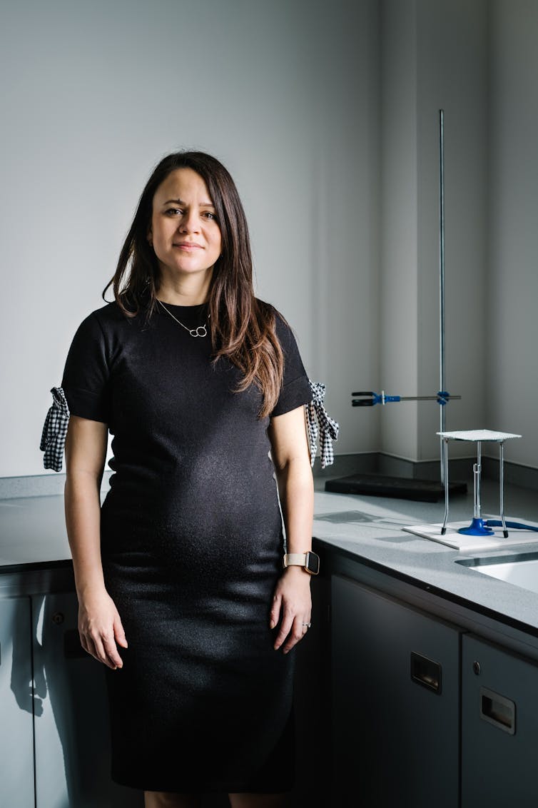 School teacher standing in front of science equipment in class room