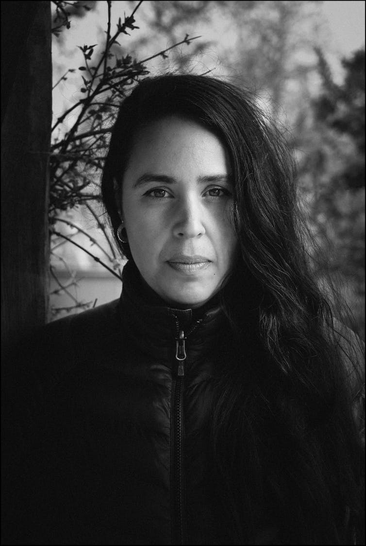 Portrait of woman standing in front of trees in a park