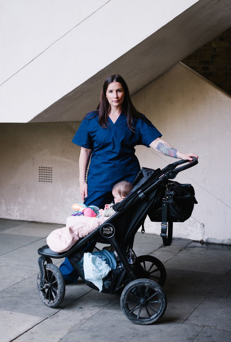 Midwife standing at the bottom of a stairway with her daughter in a pram