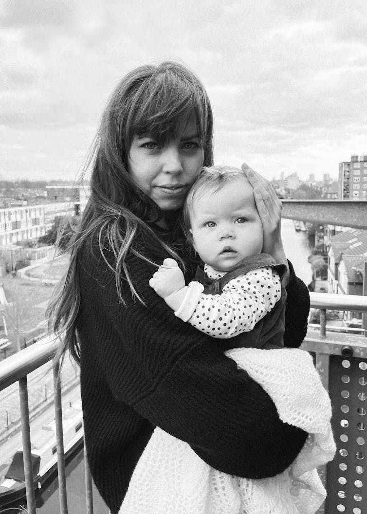 Woman holding her daughter on a balcony overlooking a canal