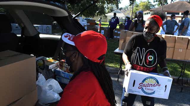 Volunteers load donated food into a car.