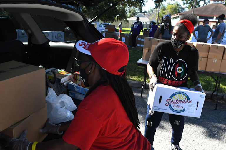 Volunteers load donated food into a car.