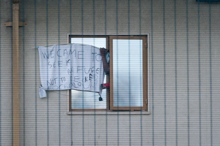 Window with a sign on it reading 'we came to seek refuge, not to be locked up' outside Yarl's Wood Immigration Removal Centre