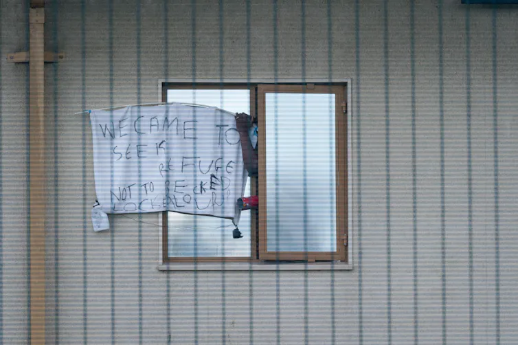 Window with a sign on it reading 'we came to seek refuge, not to be locked up' outside Yarl's Wood Immigration Removal Centre