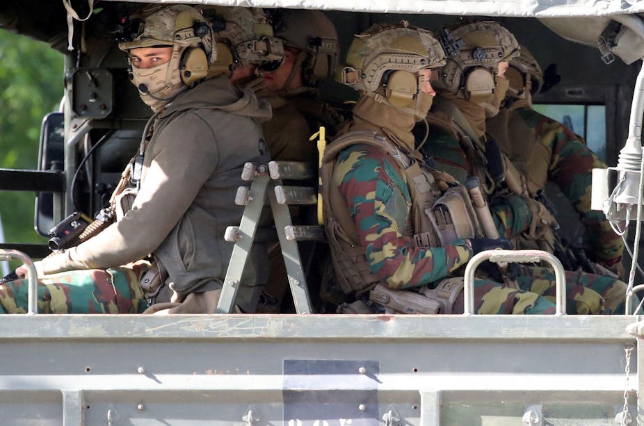 Belgian soldiers in full gear sitting in the back of a truck.