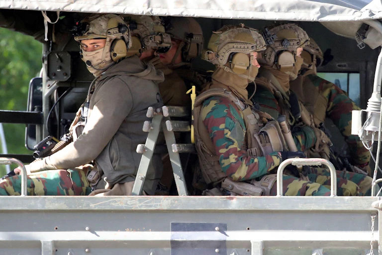 Belgian soldiers in full gear sitting in the back of a truck.