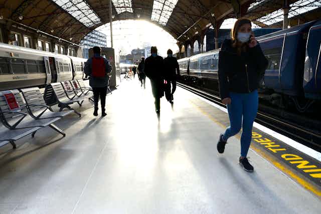 Passengers walk along the platform in Victoria rail station, London