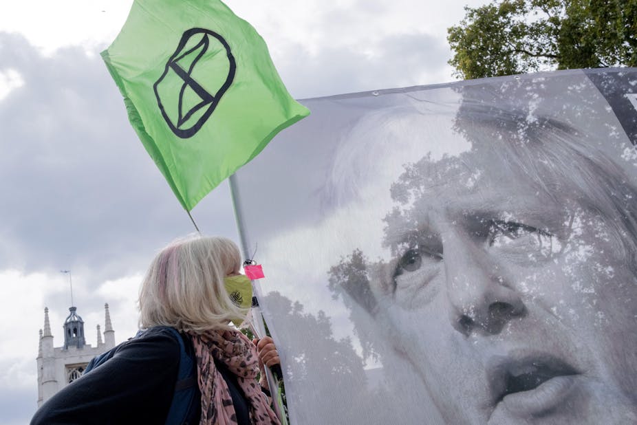 Climate change protester with a banner of Boris Johnson