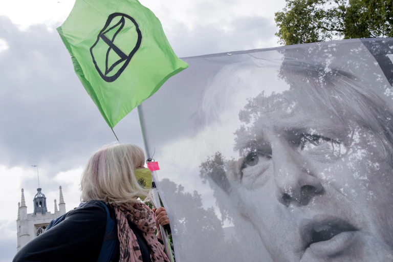 Climate change protester with a banner of Boris Johnson