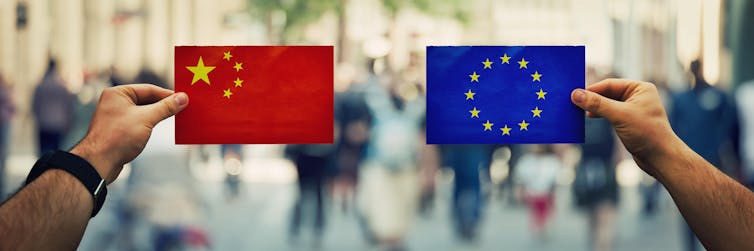 Hands holding up flags of China and EU