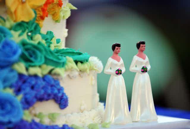 A wedding cake with statuettes of two women.
