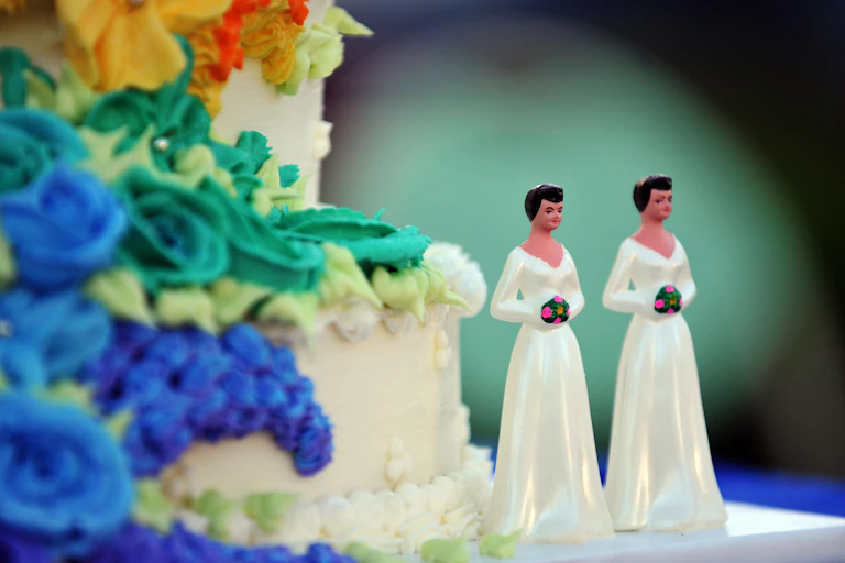 A wedding cake with statuettes of two women.