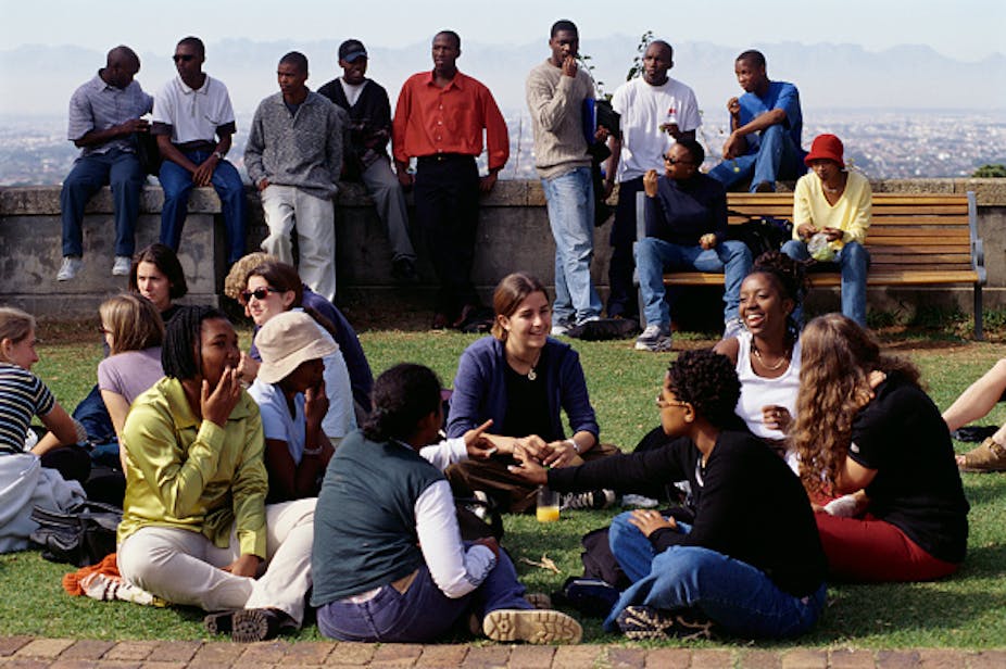 Young people sit and stand in groups outdoors