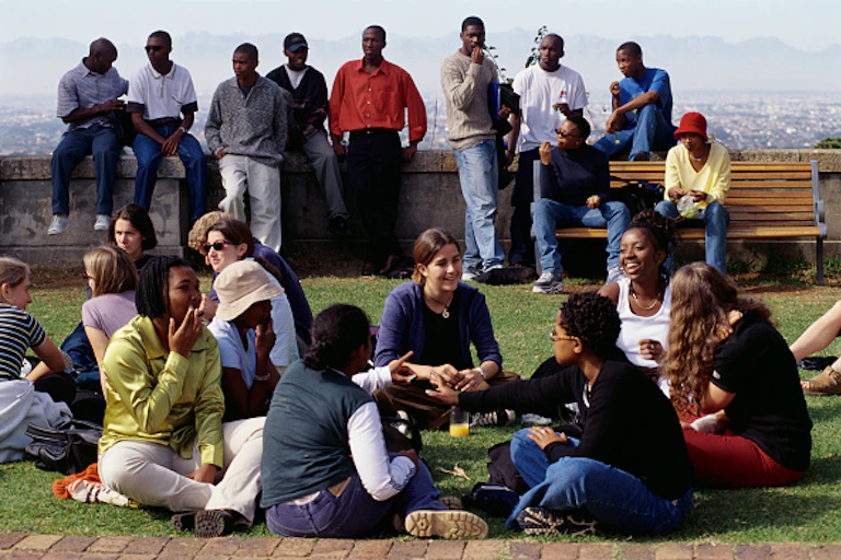 Young people sit and stand in groups outdoors