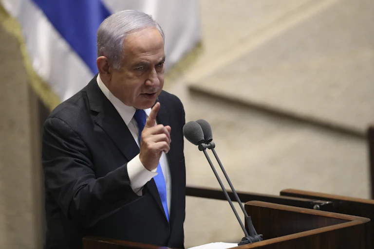 A man gestures while standing at a microphone