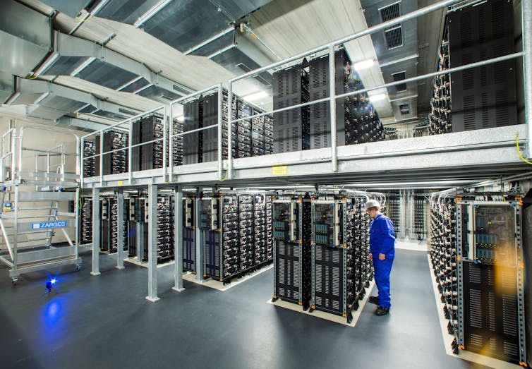 An engineer inspects stacked rows of power storage units.