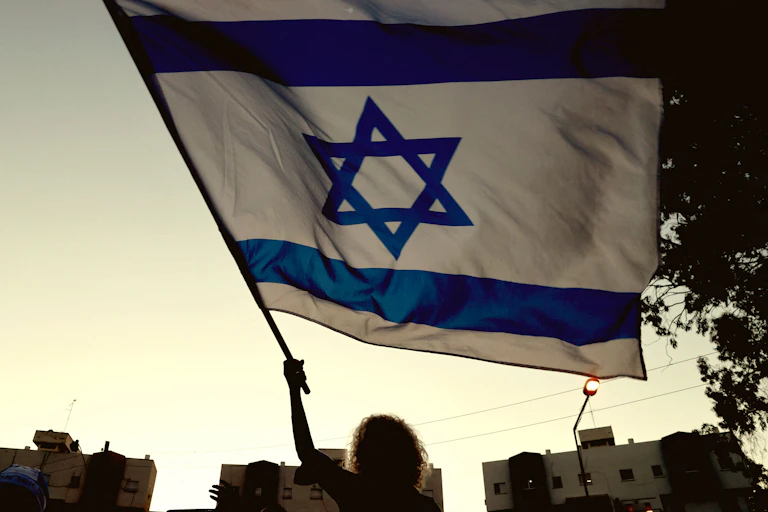 Woman waves an Israeli flag at dusk