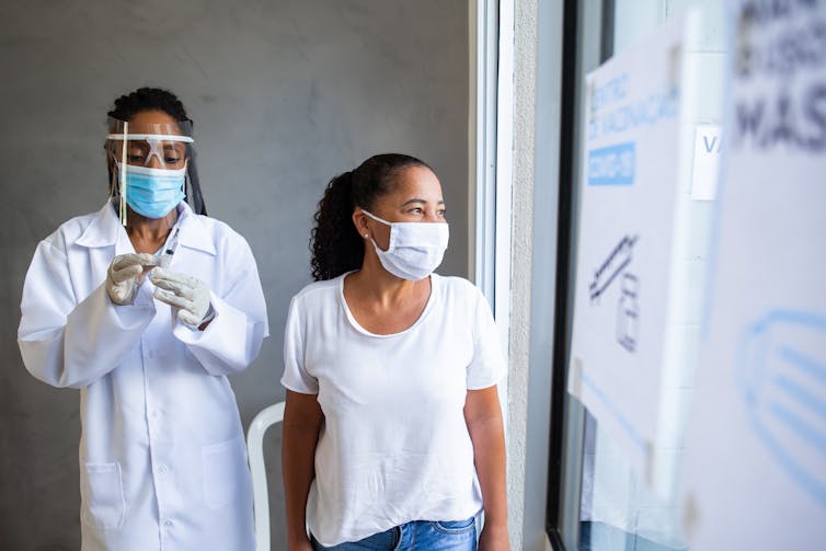 Person about to get vaccinated by healthcare provider looks out a window.