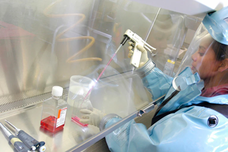 Jeune scientifque couverte d'un combinaison pressurisée manipule des instruments.