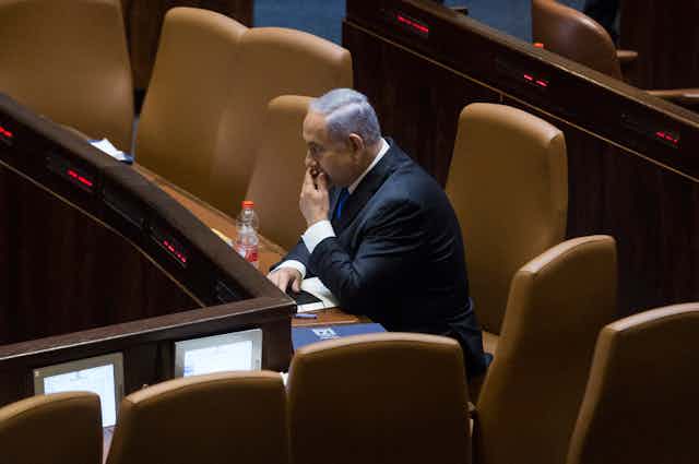 Benjamin Netanyahu sitting alone in the Israeli Parliament as he awaits the vote that could oust him from his longtime job.
